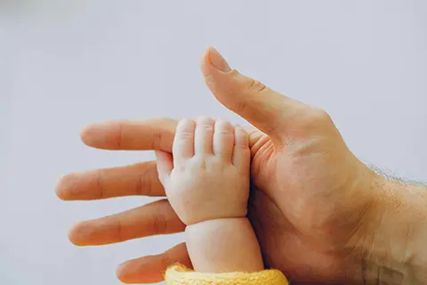 photo of a babies hand touching an adults hand